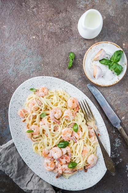 Espaguetis de pasta italiana en salsa cremosa con camarones en un plato, vista superior