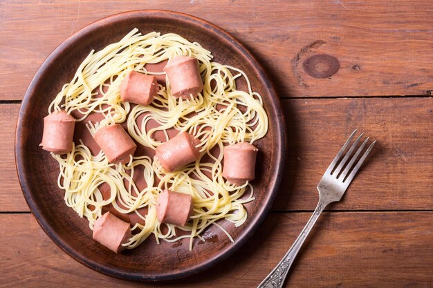 Foto espaguetis de pasta con salchicha sobre fondo rústico