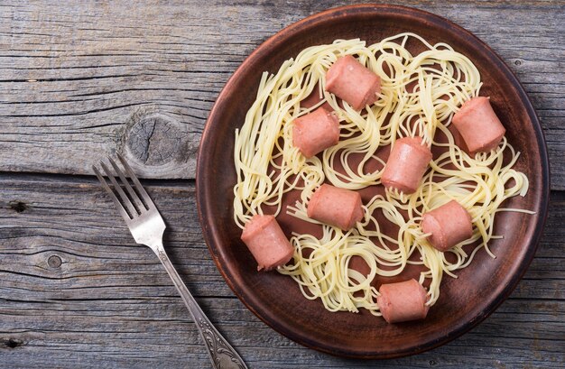 Foto espaguetis de pasta con salchicha sobre fondo rústico