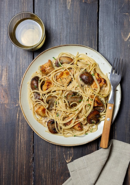 Espaguetis de pasta en salsa cremosa con pollo y champiñones. Comida italiana.