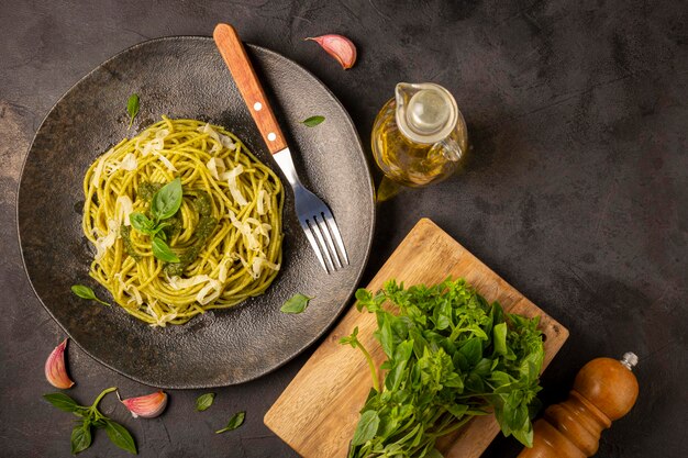 Espaguetis de pasta con salsa pesto y hoja de albahaca.