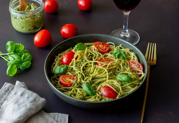 Espaguetis de pasta con salsa pesto, tomate y albahaca. Alimentación saludable. Comida vegetariana.