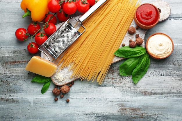 Espaguetis de pasta con tomate, queso y albahaca sobre fondo de madera de color