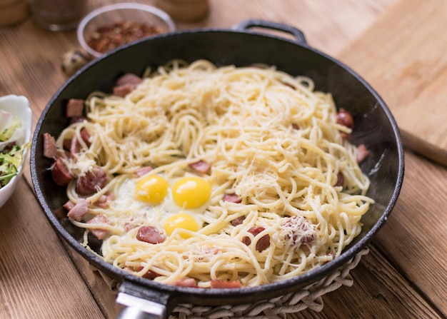 Espaguetis con queso de salchichas y huevos de codorniz en una sartén