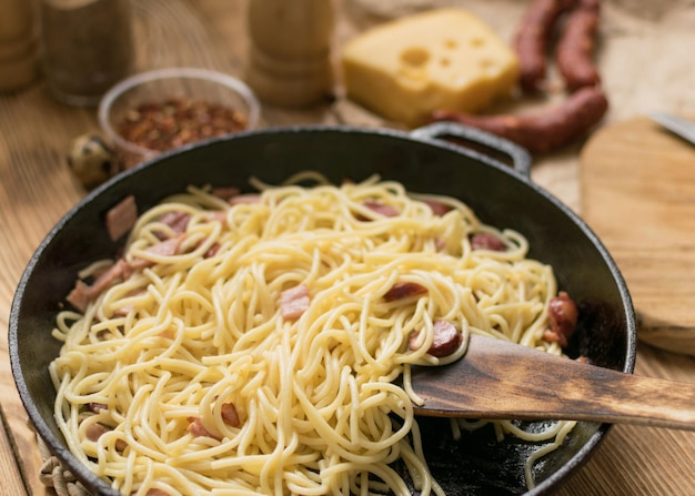 Espaguetis con queso de salchichas y huevos de codorniz en una sartén