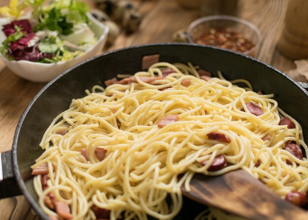 Espaguetis con queso de salchichas y huevos de codorniz en una sartén