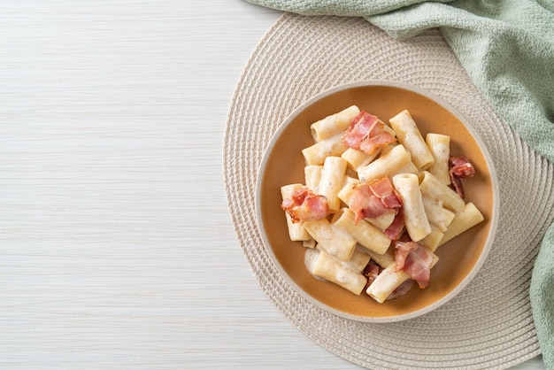 espaguetis rigatoni caseros con salsa blanca y tocino - estilo de comida italiana