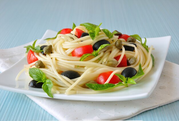 Espaguetis con rodajas de tomate y aceitunas, alcaparras y albahaca