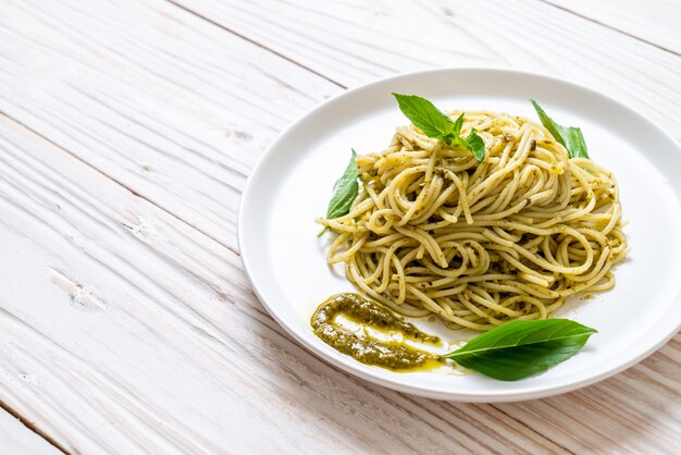 Espaguetis con salsa de pesto, aceite de oliva y hojas de albahaca.