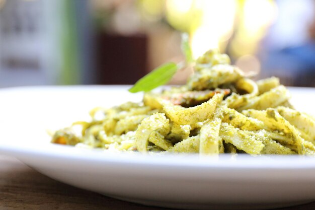 Espaguetis con salsa pesto sobre fondo de madera