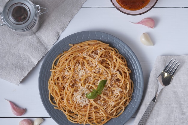 Espaguetis con salsa de tomate y parmesano. Pasta en una mesa de madera blanca. Plato italiano para el almuerzo. Vista superior.