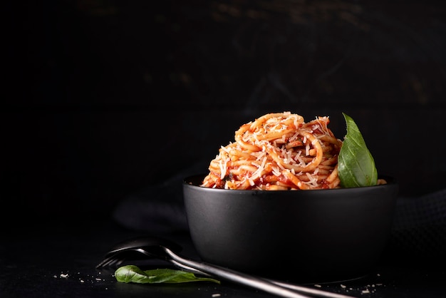 Espaguetis con salsa de tomate y parmesano en tazón negro