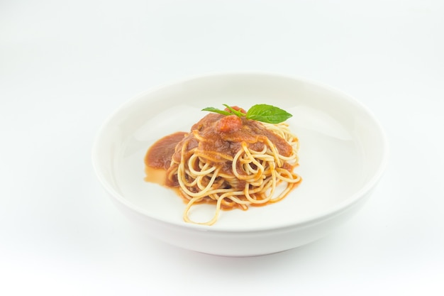 Espaguetis con salsa de tomate en plato blanco sobre fondo blanco.