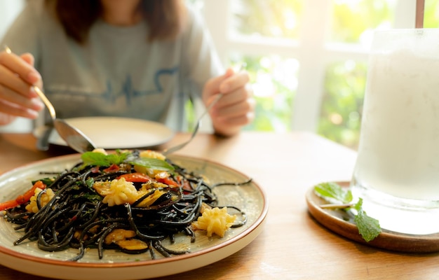 Espaguetis de tinta de sepia negra con gambas en un plato Pasta negra con tinta de calamar en una mesa de restaurante