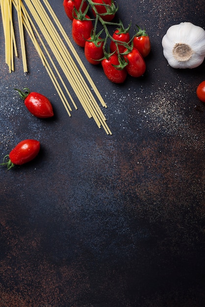 Espaguetis, tomate y ajo en la mesa negra