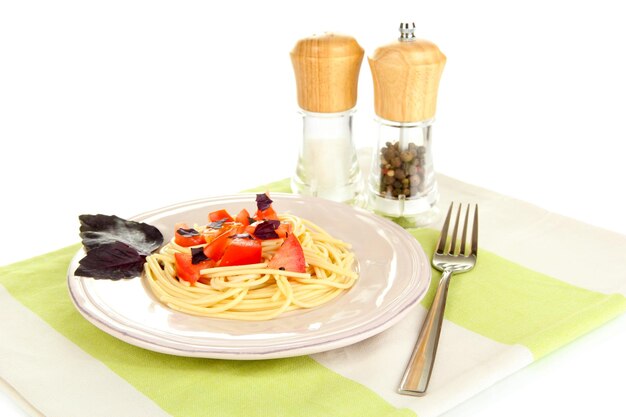 Espaguetis con tomates y hojas de albahaca en servilleta aislado en blanco