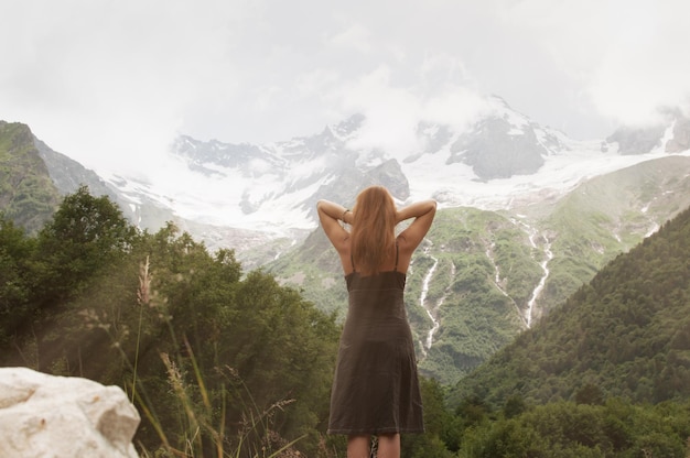 Espalda de mujer cogida de la mano entre montañas