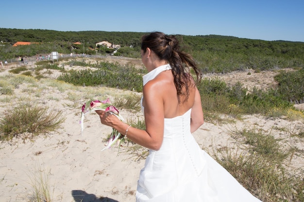 espalda de la novia después de la boda en la playa de arena en verano