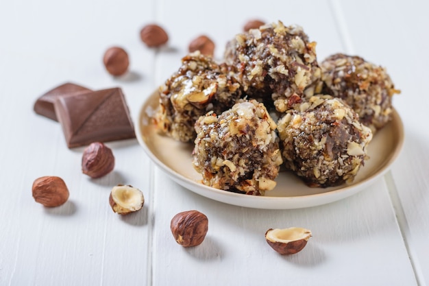 Espalhados em uma mesa branca avelãs e doces de nozes raladas e frutas secas em uma mesa branca. Deliciosos doces caseiros frescos.