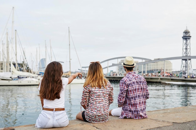 Espanha, Barcelona, três turistas sentados em um píer na cidade