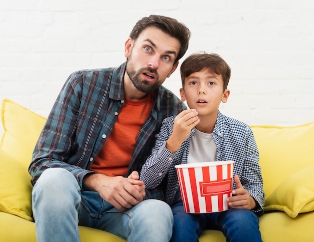 Espantado pai e filho assistindo tv