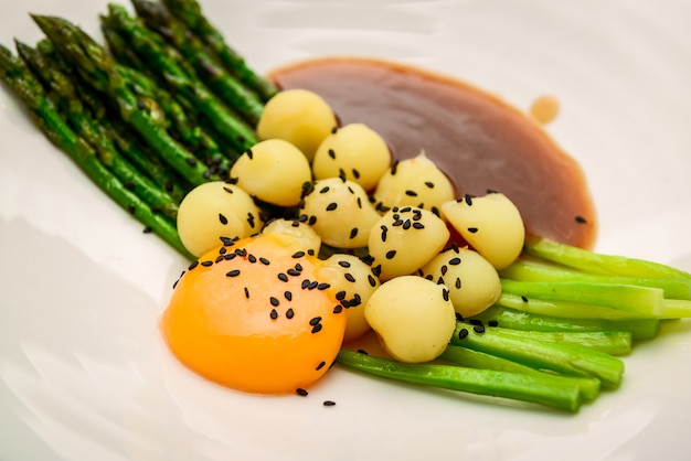 Espargos com batatas, com molho de carne e gema de ovo