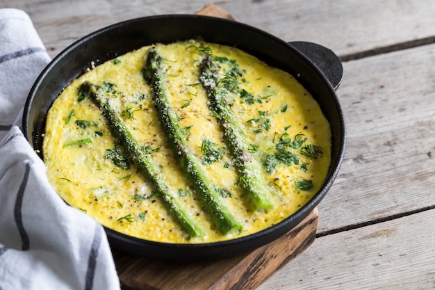 Espargos com ovos mexidos. Omelete com aspargos em uma frigideira.