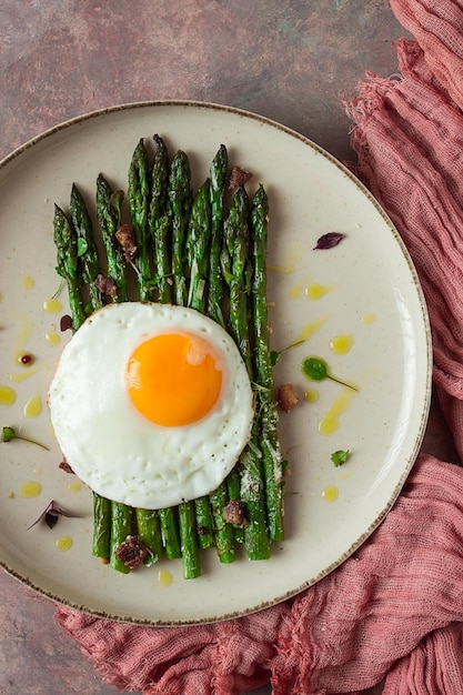 Espargos grelhados com especiarias de ovo frito e ervas queijo parmesão em um prato bege vista superior rústico sem pessoas