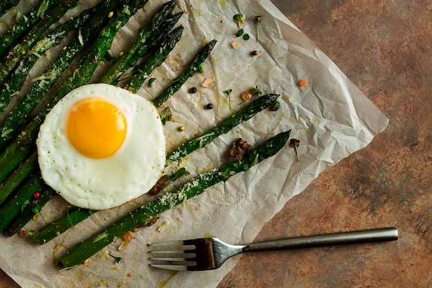 Espargos grelhados com especiarias de ovo frito e ervas queijo parmesão em uma vista superior de papel rústico sem pessoas