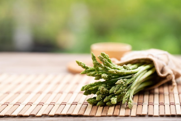 Espargos são vegetais verdes e retos Os espargos verdes frescos são crocantes para cozinhar na mesa de madeira com sal