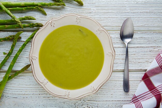 Espargos sopa verde creme na mesa de madeira branca