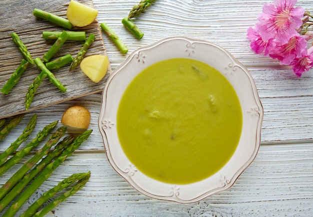 Espargos sopa verde creme na mesa de madeira branca