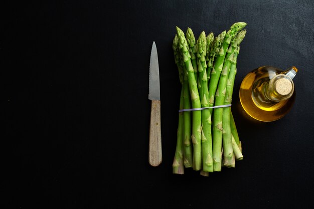 Espargos verdes em superfície escura prontos para cozinhar