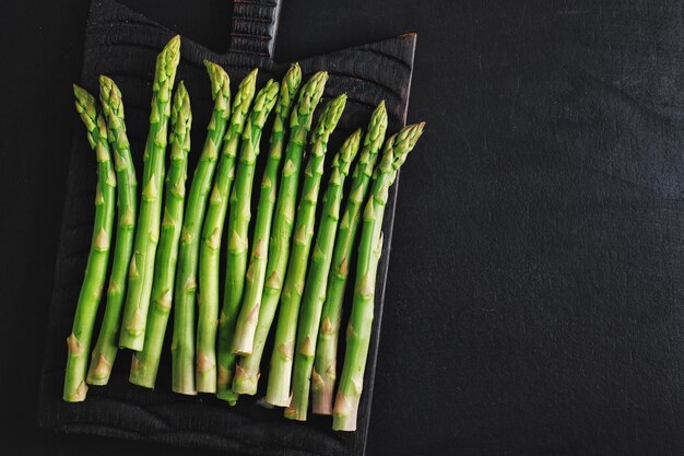 Espargos verdes em superfície escura prontos para cozinhar