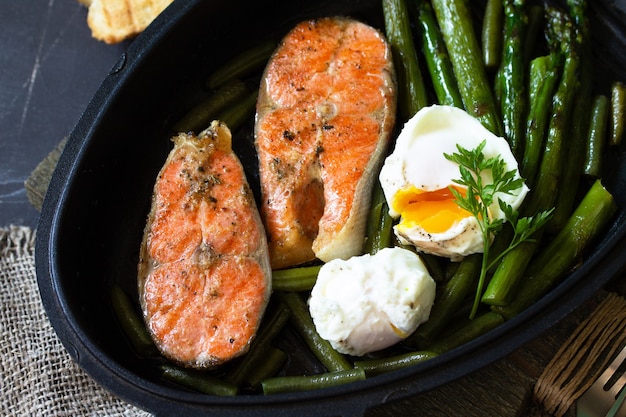 Espargos verdes grelhados com salmão e ovos escalfados Comida saudável em fundo de madeira rústico