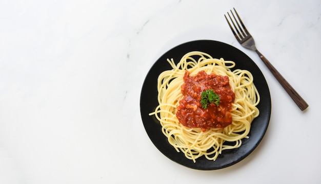 Esparguete à bolonhesa, vista superior - macarrão italiano de espaguete servido na chapa preta com molho de tomate e salsa