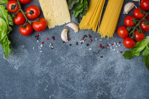 Esparguete de macarrão cru italiano e ingredientes de cozinha tomates cereja queijo verdes