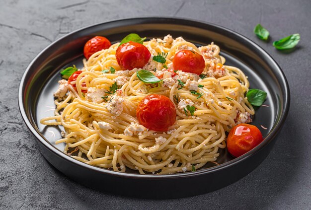 Esparguete fetapasta com queijo feta tomate cereja e ervas closeup Massa vegetariana popular com feta