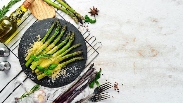 Espárragos al horno con queso y albahaca en un plato de piedra negra Vista superior Espacio libre para el texto