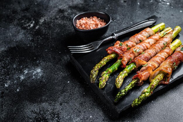 Espárragos al horno con tocino y especias Fondo negro Vista superior Espacio de copia