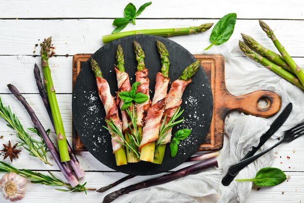 Espárragos al horno con tocino y especias en un plato de piedra negra Vista superior Espacio libre para el texto