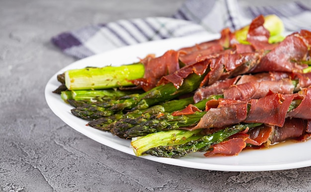 Espárragos al horno con tocino y hierbas sobre fondo de madera