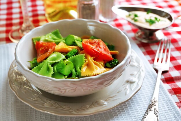 Espárragos asados y pasta sabrosa con verduras en un tazón sobre fondo de mesa de madera