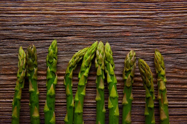 Espárragos vegetales crudos en una fila en madera envejecida