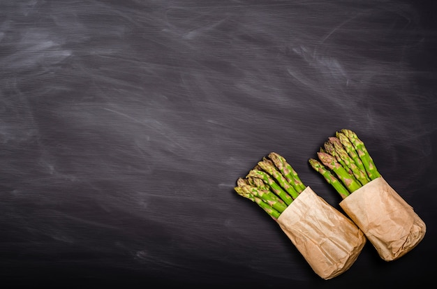 Espárragos verdes frescos sobre un fondo negro con lugar para el texto. Cosecha de primavera estacional. Endecha plana, copie el espacio. Concepto de comida sana