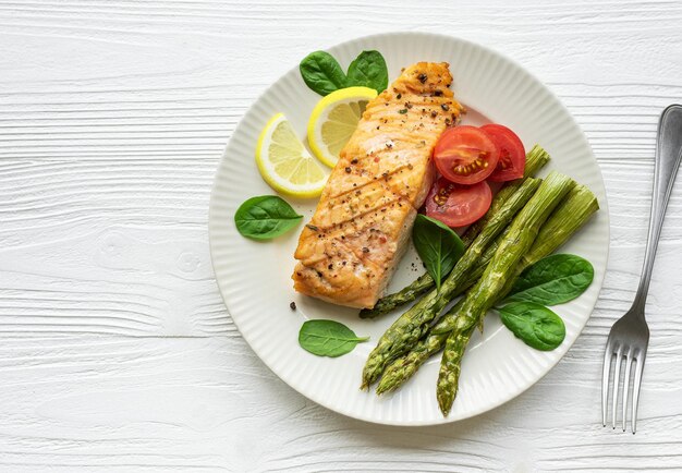 Espárragos verdes de salmón deliciosos al horno con verduras en un plato