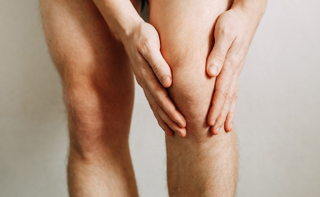 Espasmo no joelho do homem lesões nas articulações fadiga no trabalho área da lesão