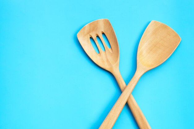 Espátula de cocina de madera sobre mesa azul.