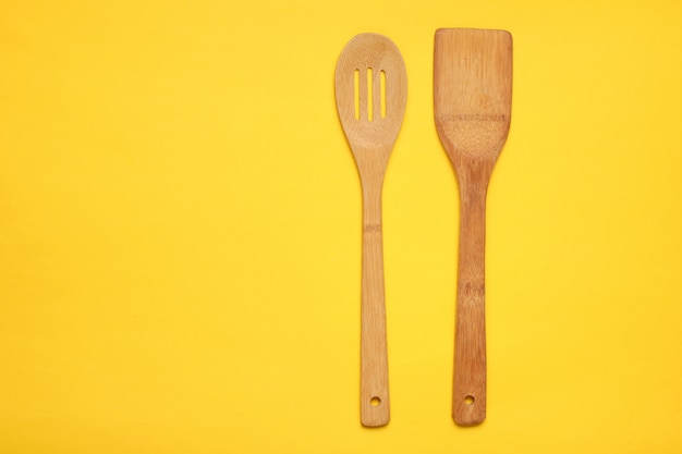 Espátula de madeira para cozinhar em uma mesa amarela. Conceito de cozinha, minimalismo