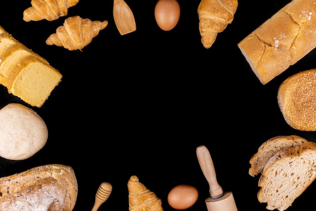 una espátula pequeña un rodillo un huevo rebanadas de pan bollos croissants y barras de pan